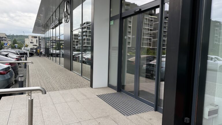 Wycieraczka aluminiowa przed wejściem w przeszklonej elewacji budynku