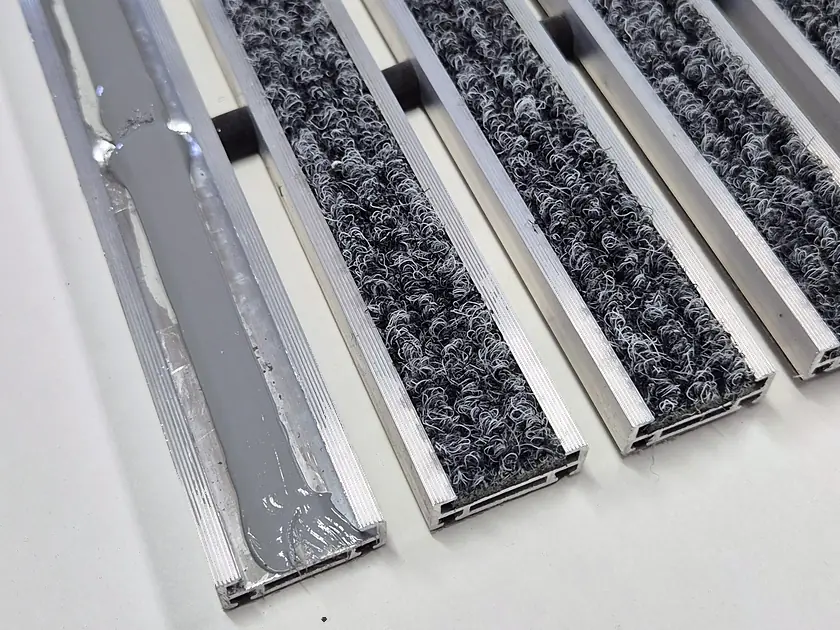 Klej montażowy rozprowadzony wewnątrz profilu aluminiowego wycieraczki